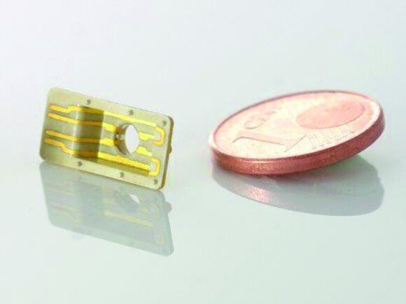 Darstellung der Mikrotechnik durch sehr kleine Linsen, elektronischen Plättchen und einem 1-Cent-Stück.